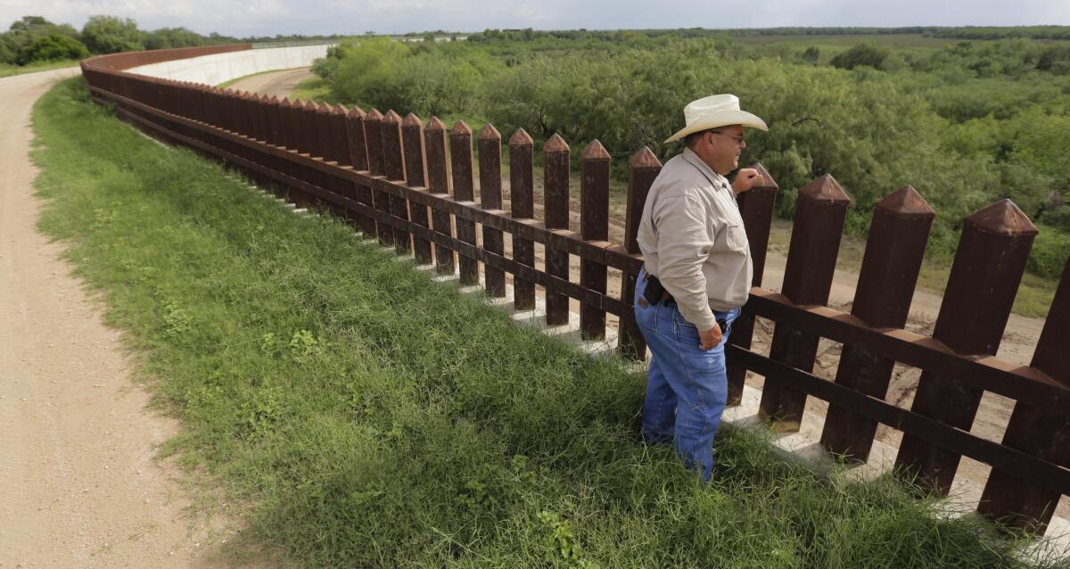 Fausto Salinas stands along the border fence in McAllen, Texas.