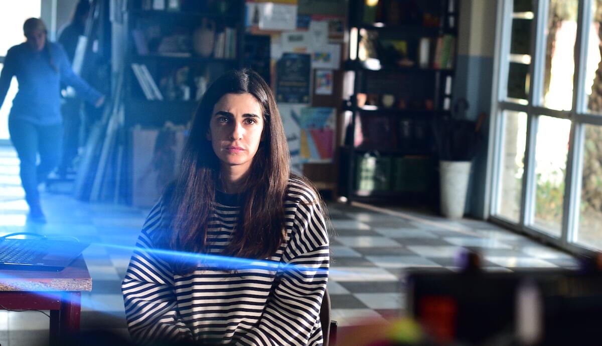 A woman wearing a striped sweater sits in a workshop.