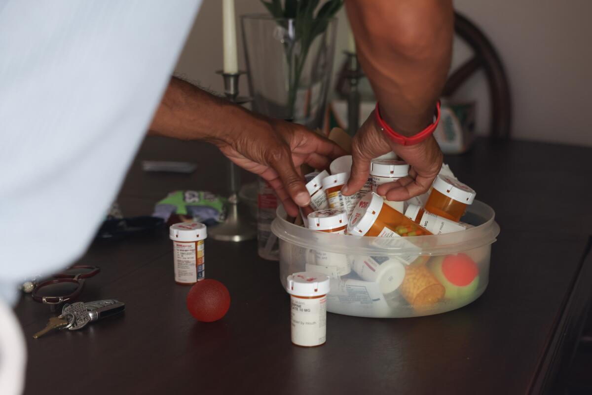A man sorts through a container of pill bottles