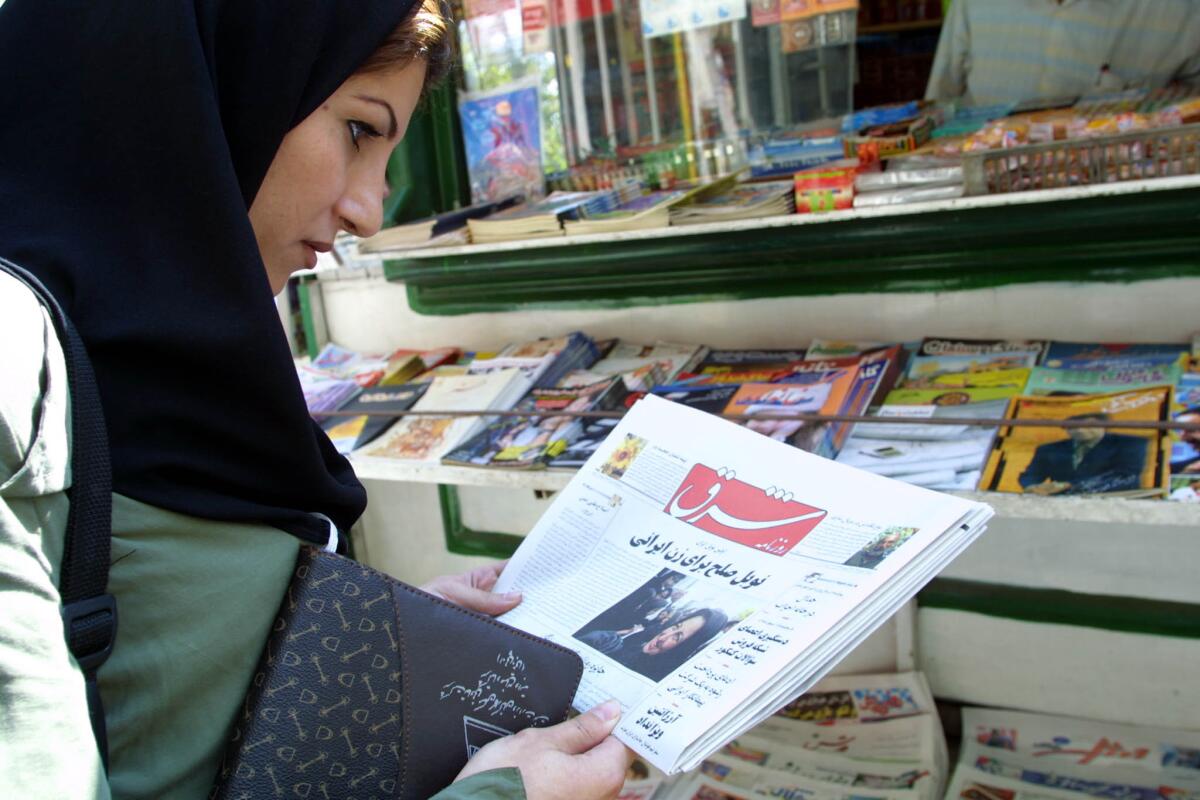 In this file photo from October 2003, an Iranian woman looks at the front page of the reformist daily Shargh in the center of Tehran.