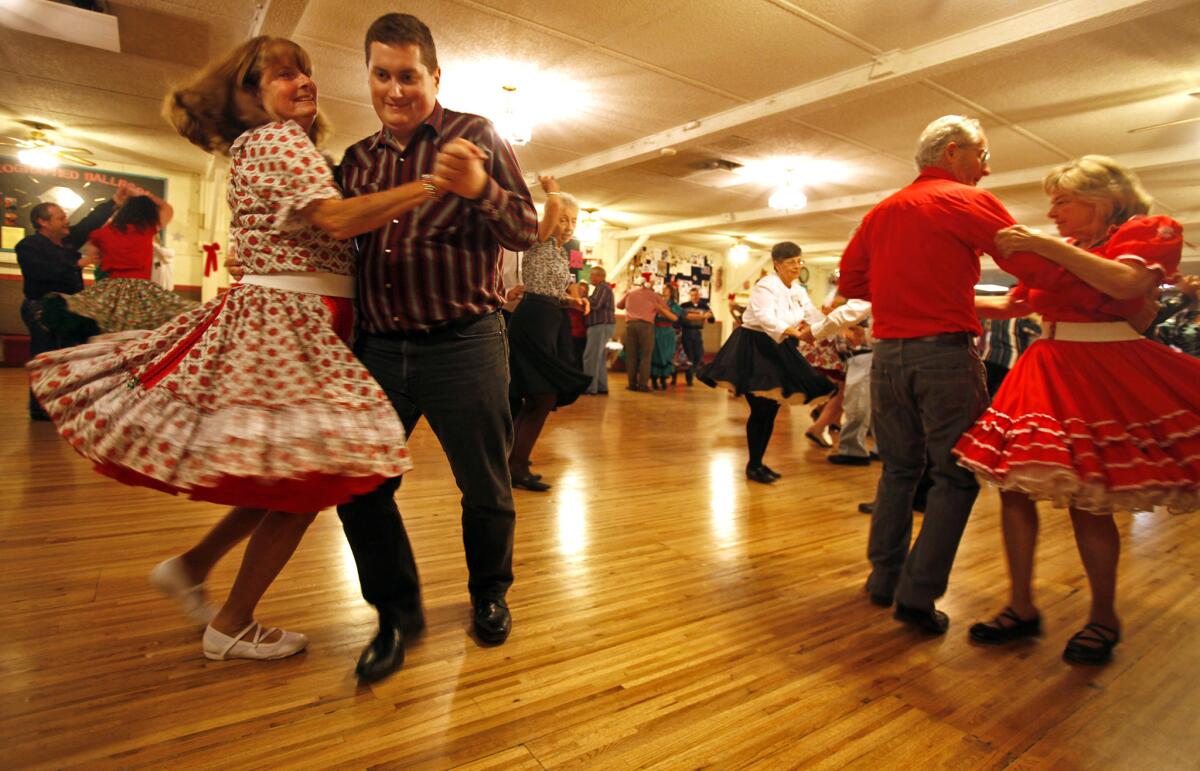 Nancy Saxon, 62, left, and Tyler Frederick, 26, twirl around the dance floor at the square-dance hall.