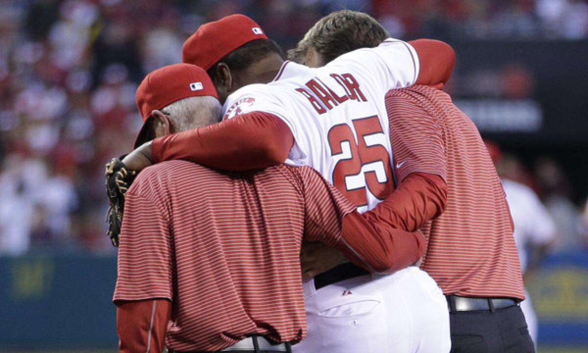 Angels hitting coach Don Baylor is helped off the field after breaking his leg while trying to catch a ceremonial first pitch during the team's season opener.