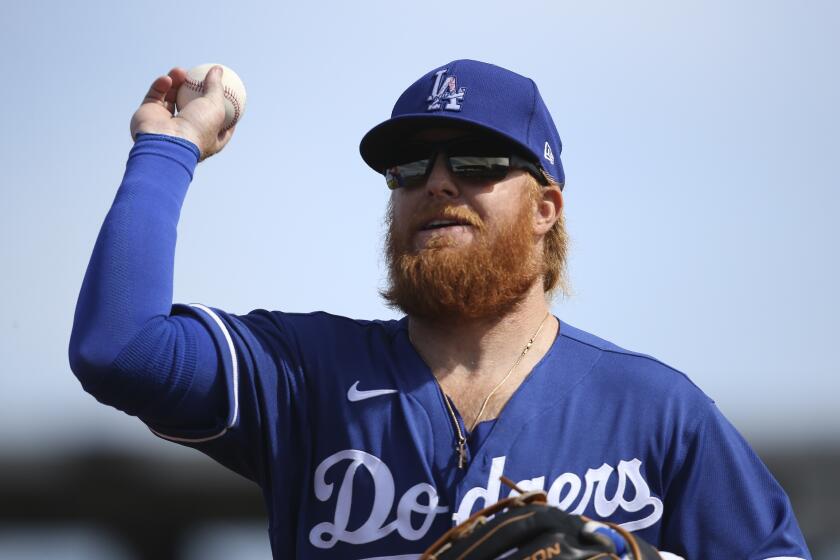 Los Angeles Dodgers third baseman Justin Turner flips the ball into the stands to a fan after the third out against the Cleveland Indians during the first inning of a spring training baseball game Thursday, Feb. 27, 2020, in Goodyear, Ariz. (AP Photo/Ross D. Franklin)