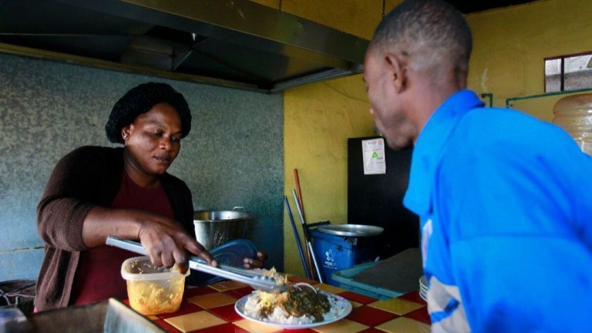 Theresa Moise, who is from Haiti, serves Kesmer Mollisoint, also from Haiti, a plate of Haitian food at the Labadee restaurant where Moise works as a cook in Tijuana, Mexico on Wednesday.