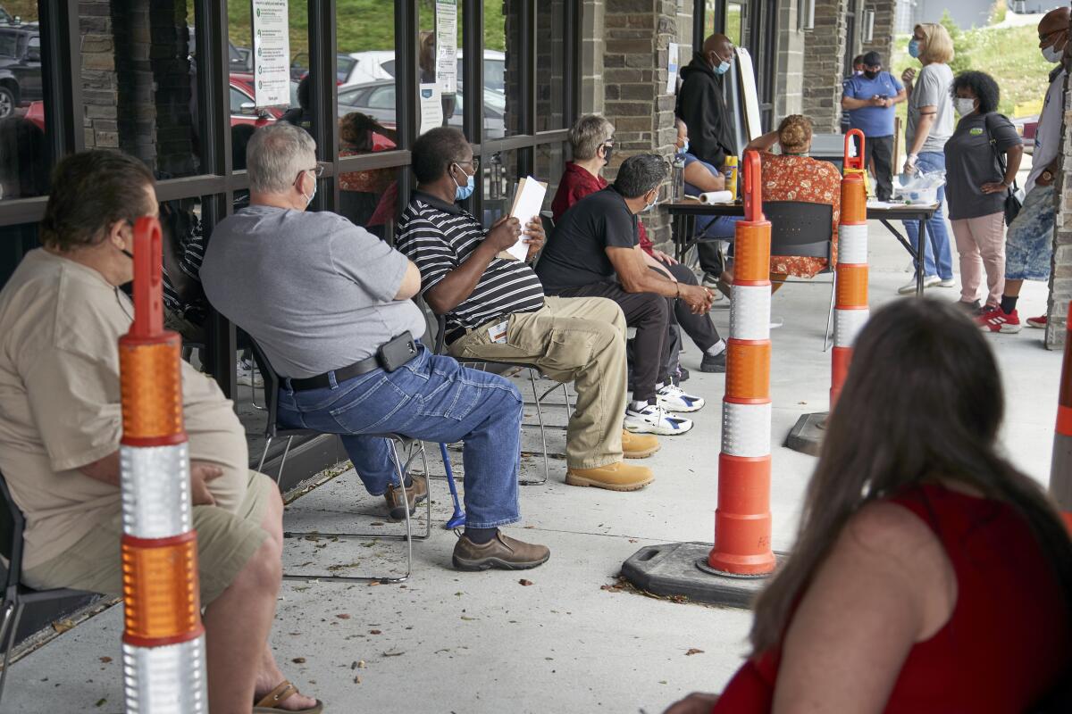 People sit in chairs in a line outside an employment services office