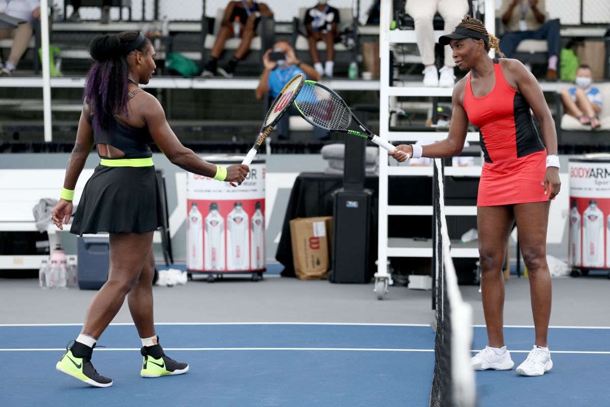 Serena, left, and Venus Williams touch rackets after their Top Seed match. 