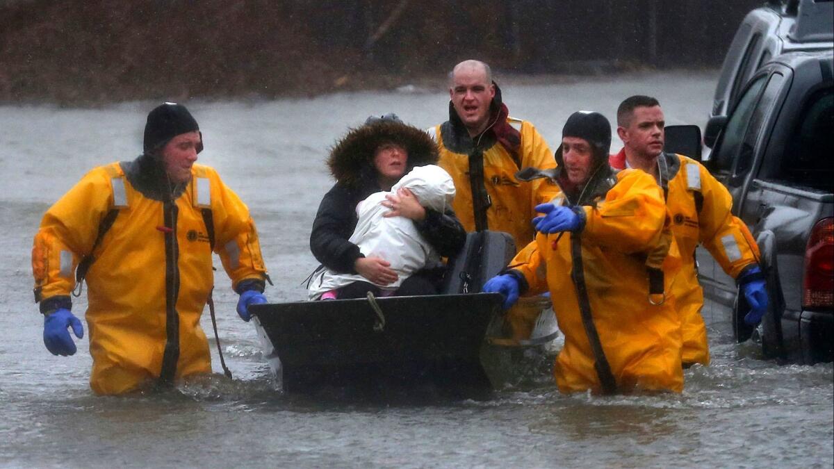 Quincy firefighters rescue a mother and child by boat after their residence was flooded along Post Island Road in the Houghs Neck section of Quincy, Mass.