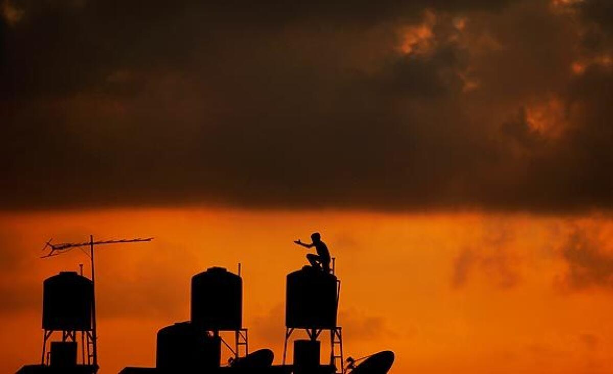 A Palestinian youth checks a rooftop water tank as the sun sets on the outskirts of the West Bank city of Ramallah.