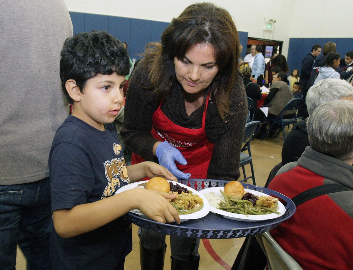 Lorena Quiroga gives instuctions her son Rocco, 6, about how to bring a plate of food to a guest at the Burbank Corps Salvation Army's annual Community Thanksgiving Dinner in Burbank on Wednesday, November 25, 2015.