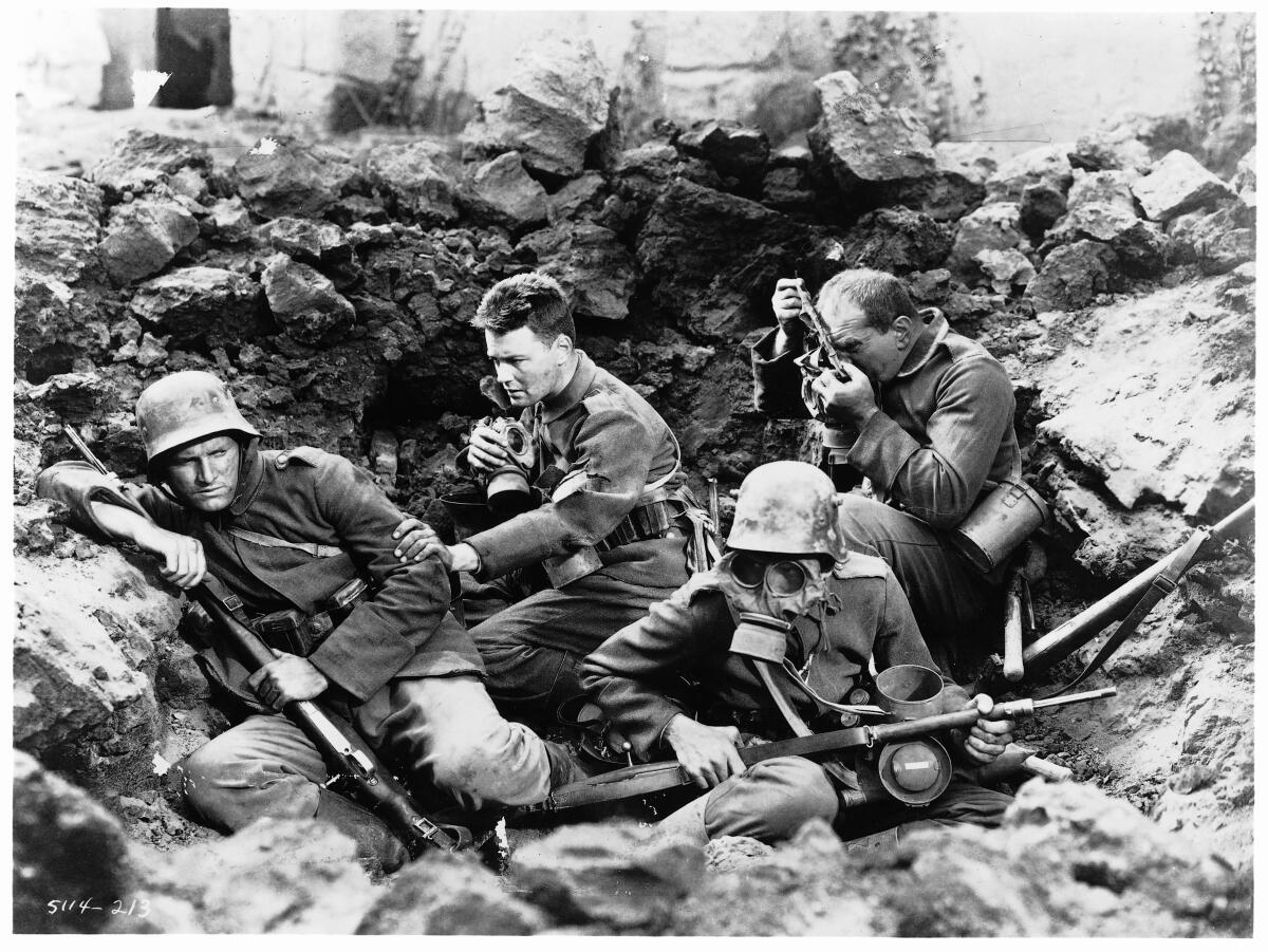 Soldiers in a trench with rifles, one wearing a gas mask in the 1930 version of "All Quiet on the Western Front."