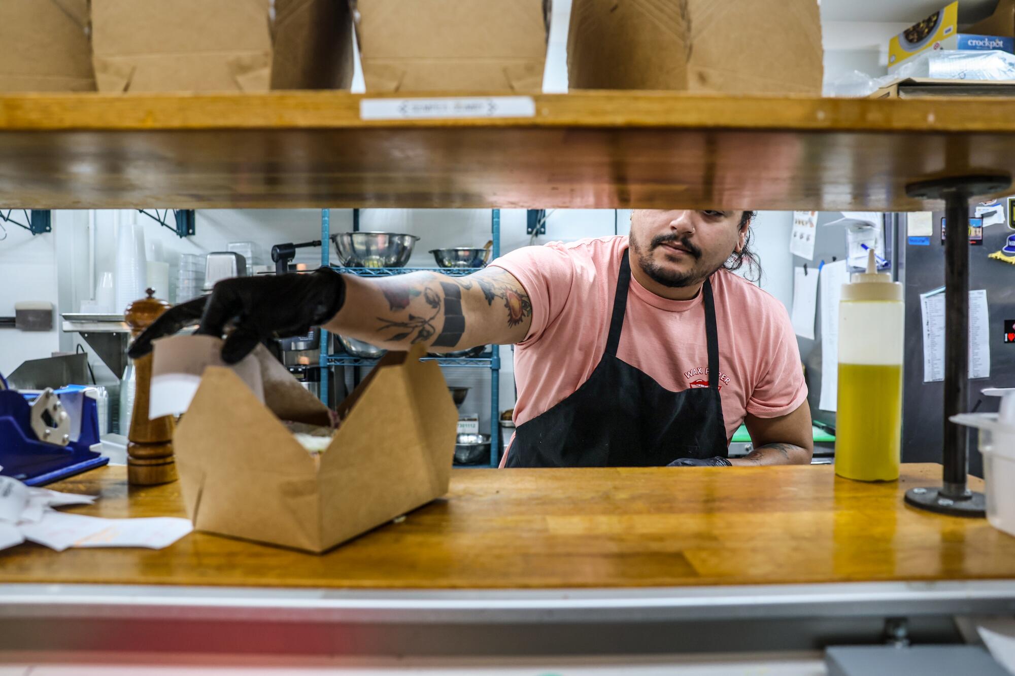 A chef in a restaurant kitchen finishes up a sandwich order at Wax Paper.  