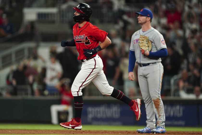 Atlanta Braves' Dansby Swanson runs past New York Mets first baseman Pete Alonso (20) after hitting a solo home run during the sixth inning of a baseball game Friday, Sept. 30, 2022, in Atlanta. (AP Photo/John Bazemore)