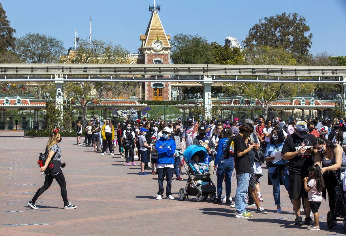 A woman walks toward groups of people waiting in several lines