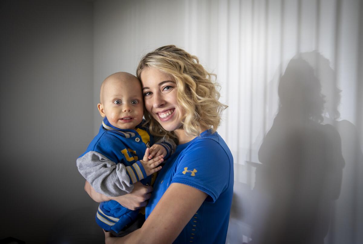 UCLA gymnast Mercedez Sanchez holds her 1-year-old brother, Liam Clark, who is battling a rare form of cancer.