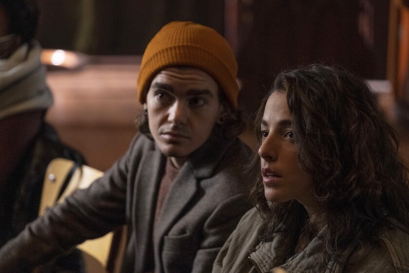 A man wearing a beanie and a woman sit side by side