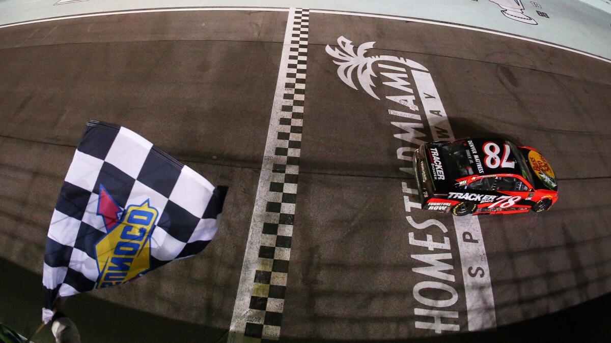 Martin Truex Jr., driver of the #78 Bass Pro Shops/Tracker Boats Toyota, crosses the finish line to win the NASCAR Cup championship and the NASCAR Cup championship Ford EcoBoost 400 at Homestead-Miami Speedway.