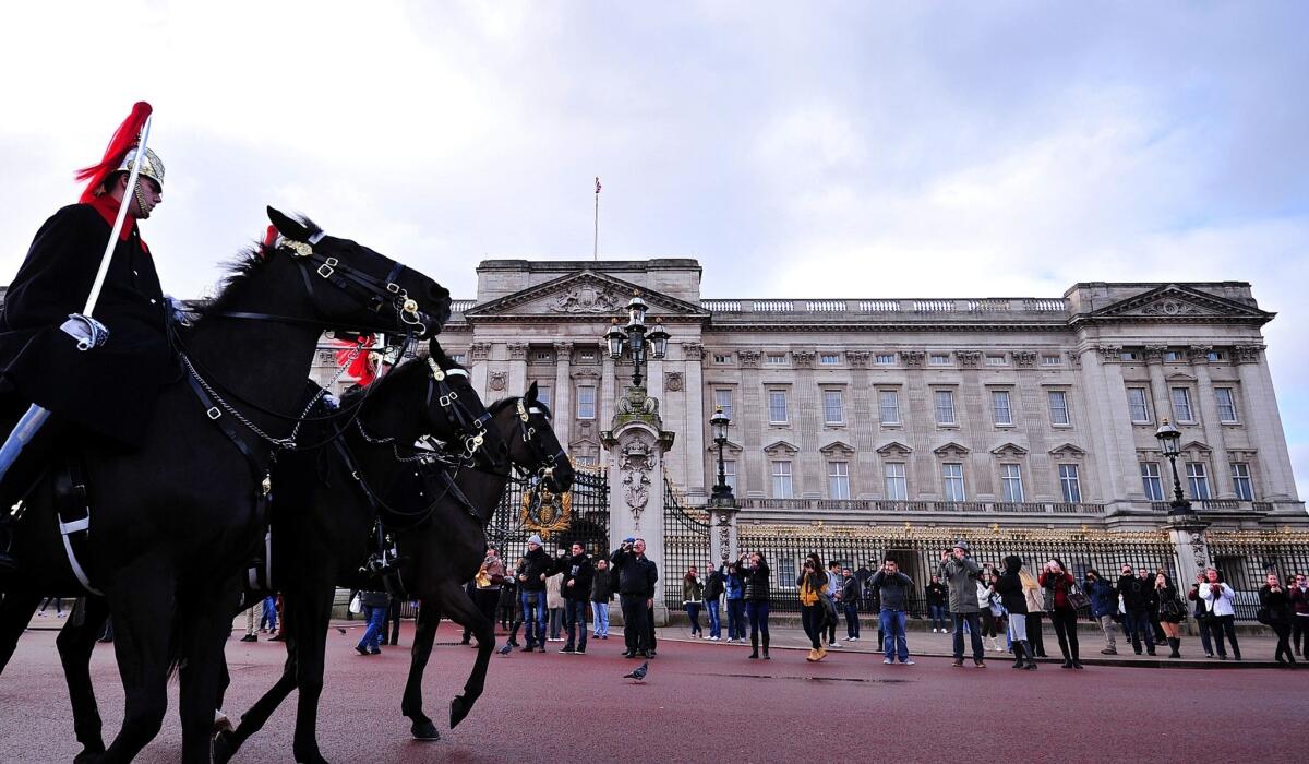 Mounted guardsmen pass Buckingham Palace in central London on Tuesday. British lawmakers on Tuesday took aim at Queen Elizabeth II's household accounts, saying they must cut costs and tackle a huge backlog of repairs to the monarch's crumbling palaces.