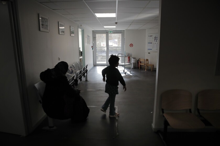 A child and his mother wait at the reception in the pediatric unit of the Robert Debre hospital, in Paris, France, Tuesday, March 2, 2021. (AP Photo/Christophe Ena)