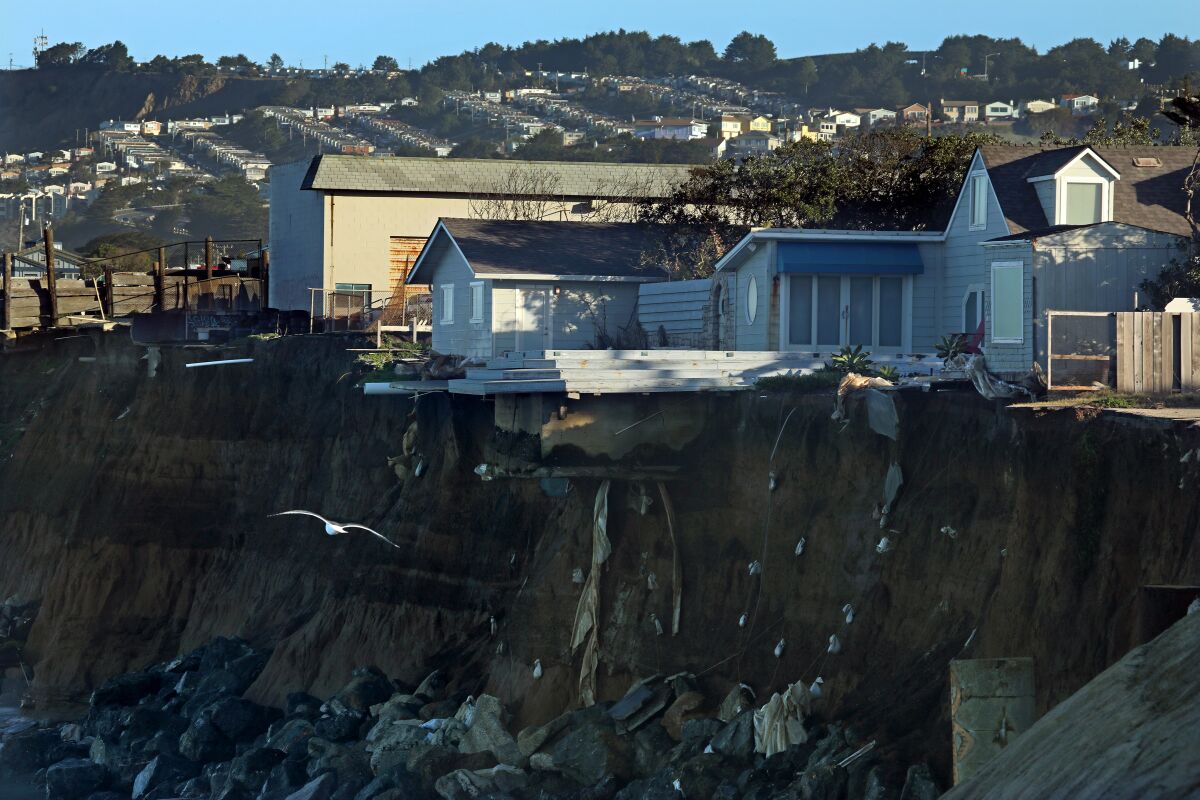 Homes dangle on the edge of a seaside cliff.