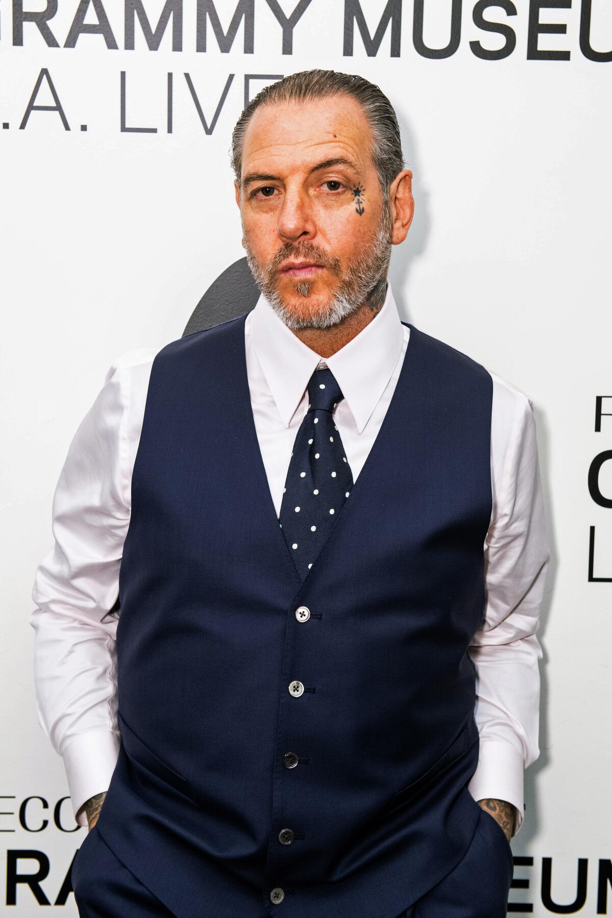 Mike Ness in a white shirt, navy vest and navy tie