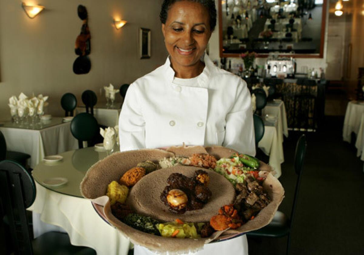 Genet Agonafer, chef and owner of Meals by Genet, holds a plate of traditional Ethiopian food offered at her restaurant in Little Ethiopia.