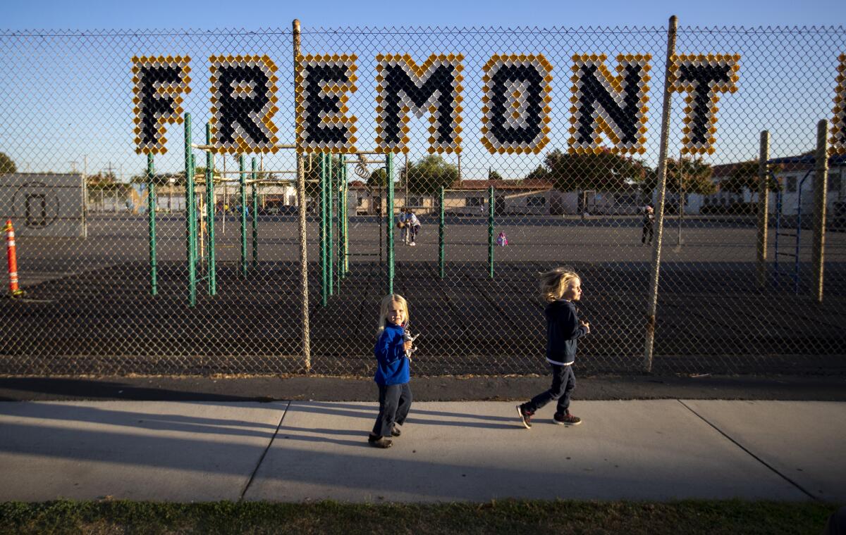 Future students run to catch up to their mother during a protest against a fence nearing completion at Fremont Elementary in Long Beach last week.