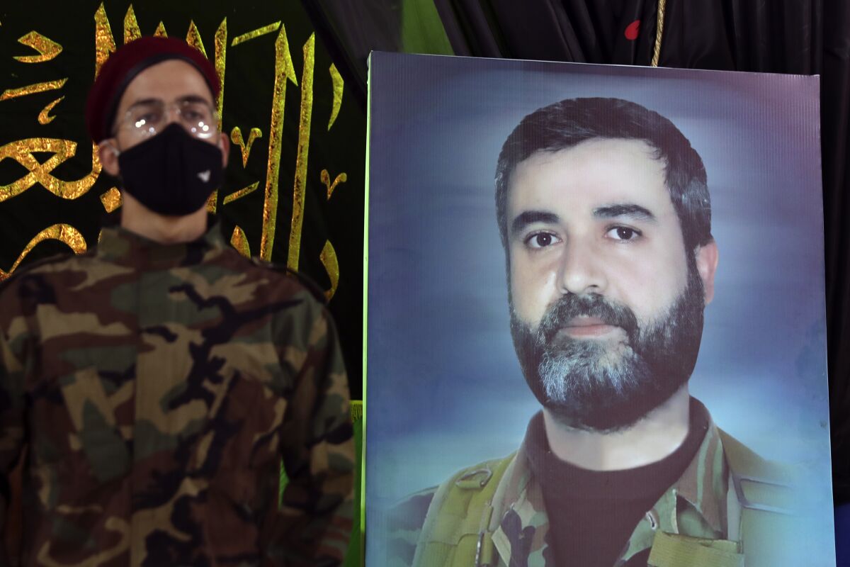 AHezbollah fighter stands next to a picture of Ali Atwa, a senior Hezbollah operative, during his funeral procession in the southern Beirut suburb of Dahiyeh, Lebanon, Saturday, Oct. 9, 2021. Atwa was placed on the FBI's most wanted list in 2001, with two other alleged participants in the 1985 hijacking of TWA Flight 847, one of the worst hijackings in aviation history and that lasted for 16 days. (AP Photo/Bilal Hussein)