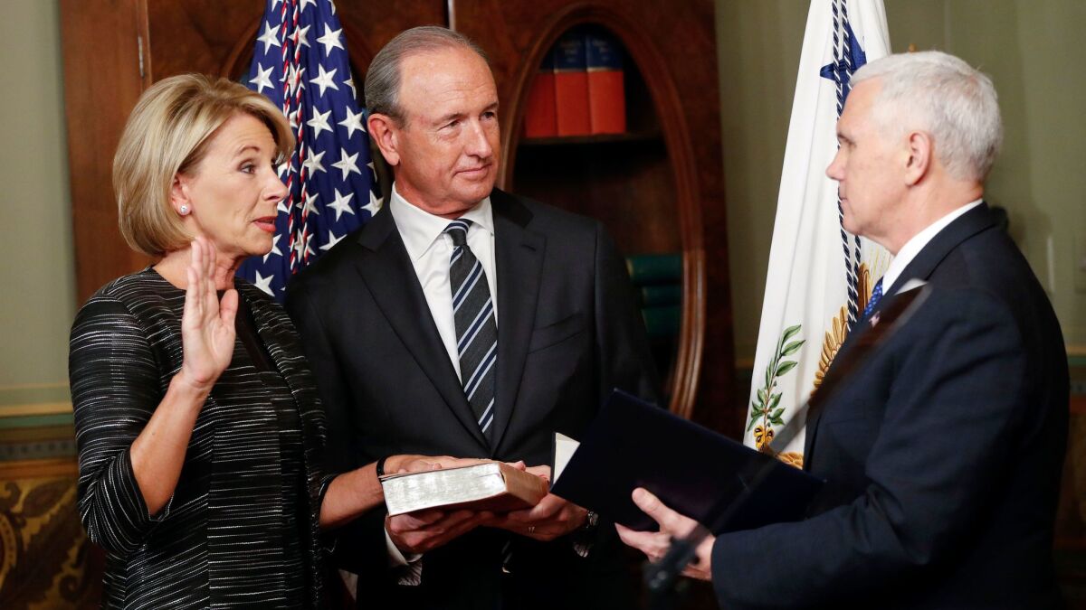 Vice President Mike Pence, right, swears in Education Secretary Betsy DeVos. They are are joined by DeVos' husband Dick DeVos.