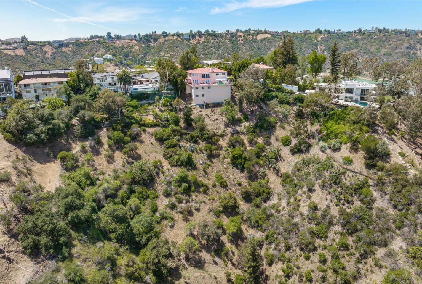 The hilltop home in an aerial view that includes greenery and sky.