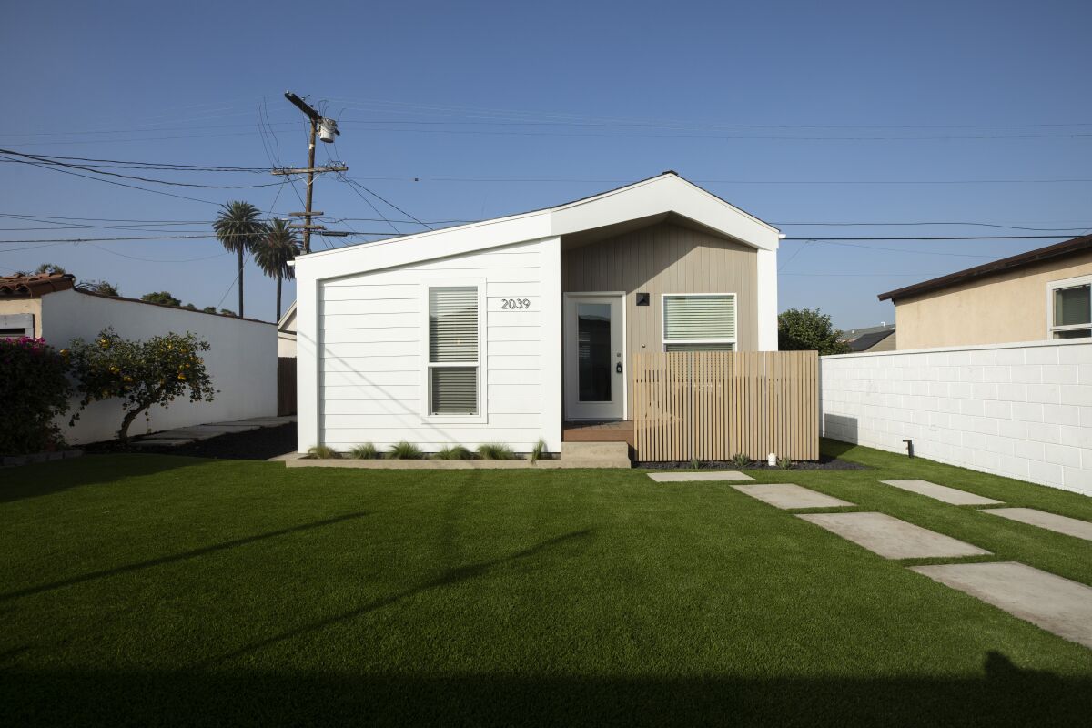 A small home with a fence on a grassy L.A. lot