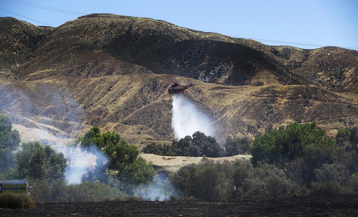 A helicopter drops its water load to stop the advance of the Manzanita fire, which has burned some 6,300 acres of rugged terrain and knocked down power poles off Highland Springs Avenue south of Beaumont. (Gina Ferazzi / Los Angeles Times)