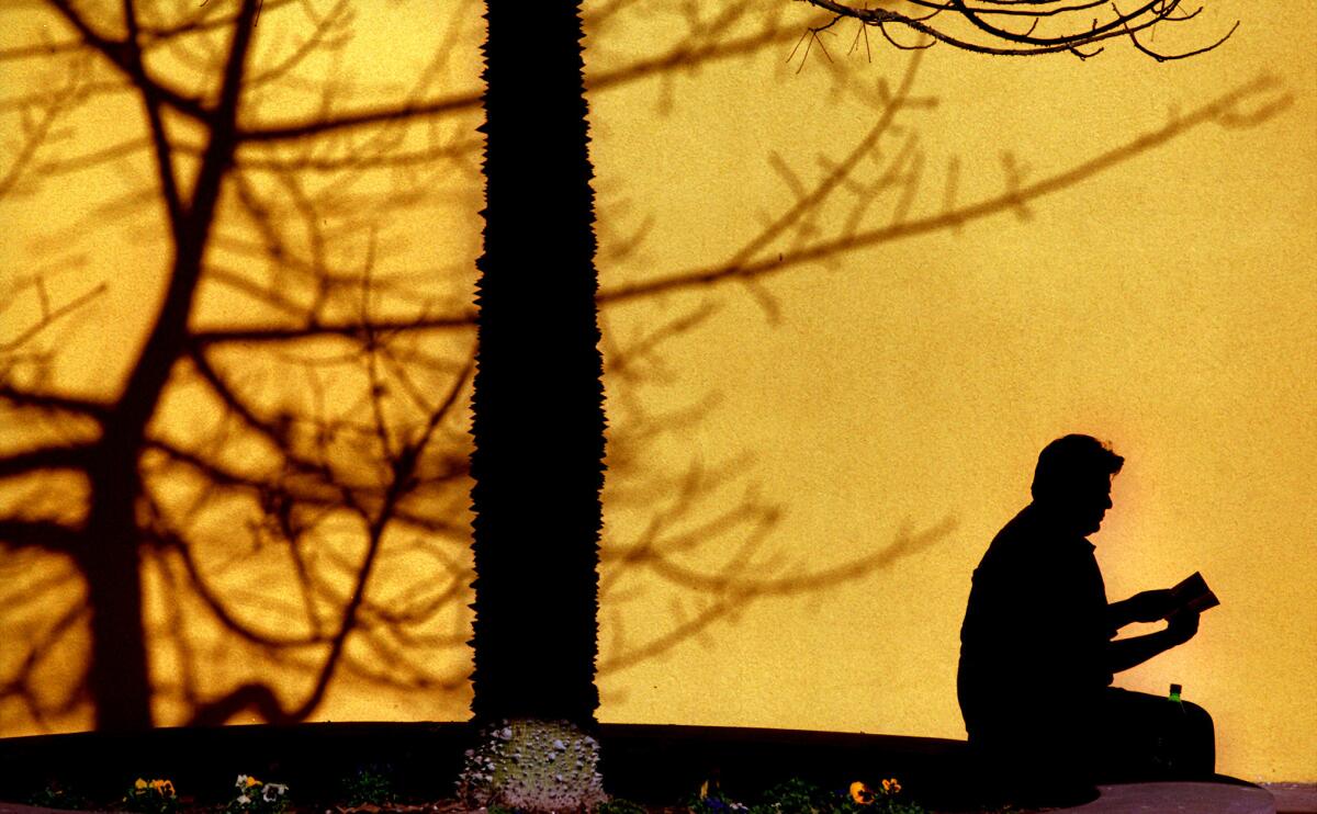 A man reading a book in Pershing Square.