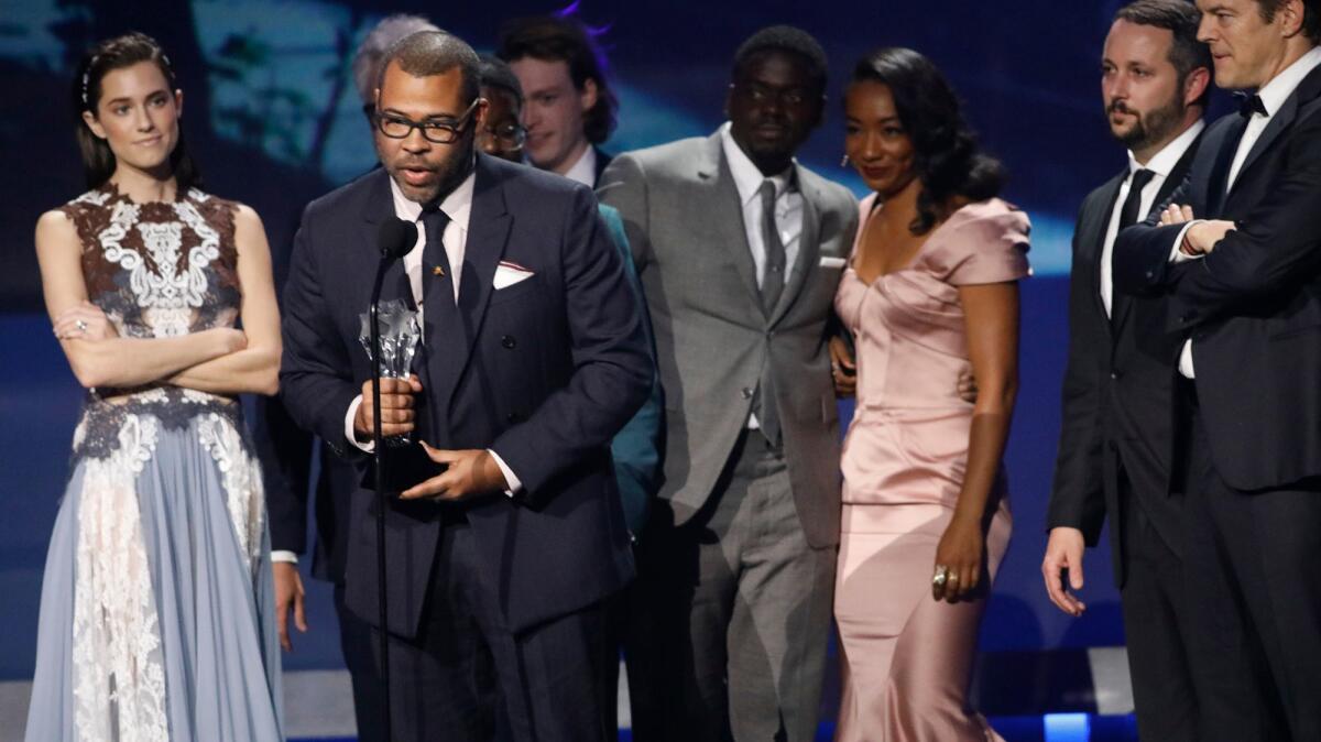 Jordan Peele gives the acceptance speech after winning the scifi/horror movie award for his film, "Get Out," with members of the cast and crew standing behind him, at the Critics Choice Awards.