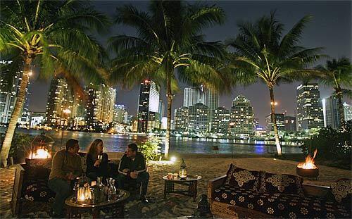 Guests enjoy balmy breezes on the palm-lined beach of the Mandarin Oriental Hotel in Miami, which is set across placid waters from the Brickell District. The Mandarin is a favorite haunt of celebrities, including Jennifer Lopez, Lenny Kravitz, Colin Ferrell and Janet Jackson.