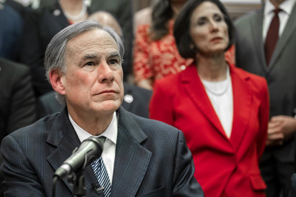 A man sits near a microphone with people behind him