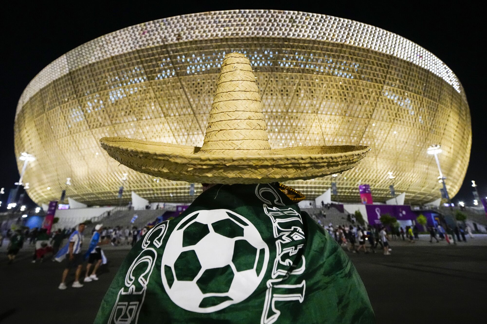 A Mexico's fan wearing a sombrero walks towards the Lusail Stadium.
