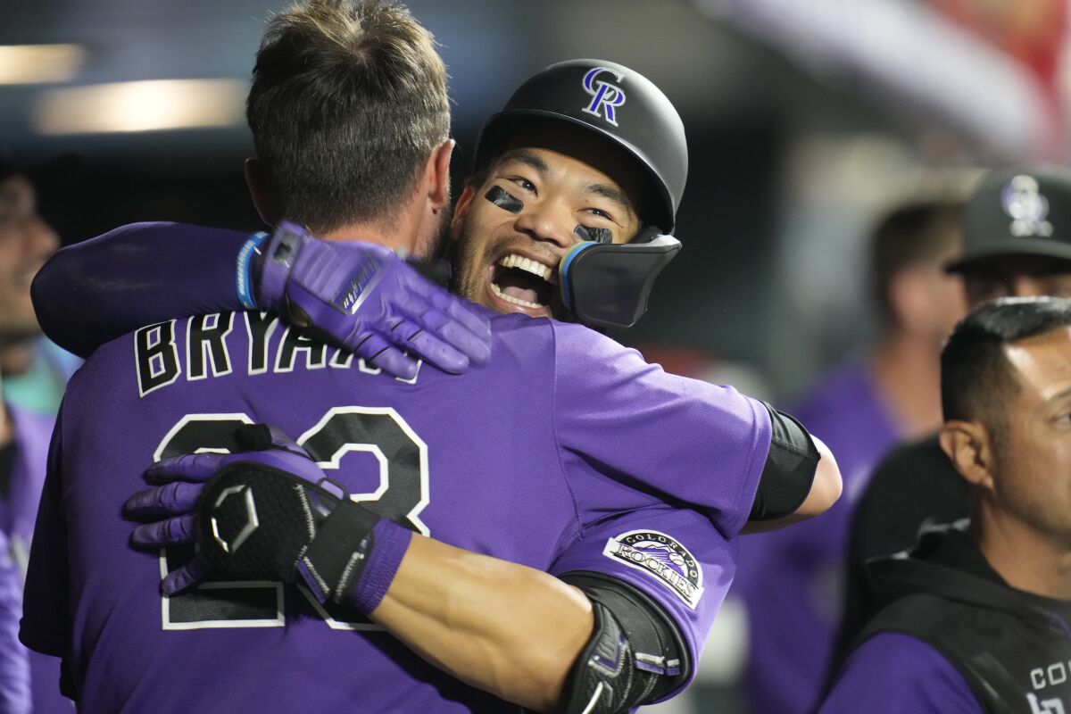 Colorado's Connor Joe, right, hugs Kris Bryant after hitting a solo home run in the eighth inning Saturday.