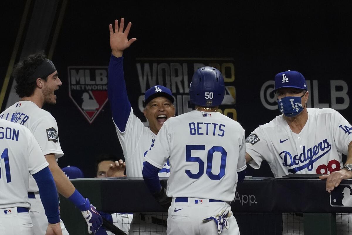 Dodgers manager Dave Roberts celebrates with Mookie Betts in the dugout.