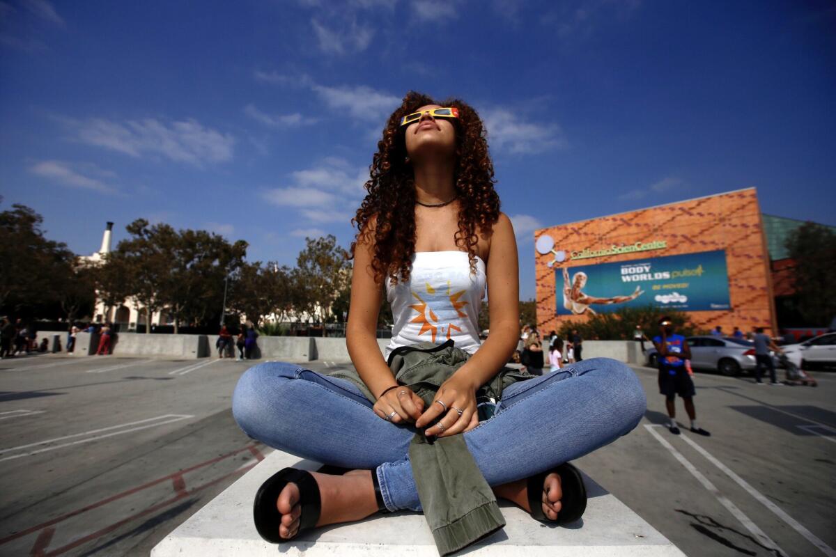 A girl wears glasses to view a partial solar eclipse at the California Science Center.