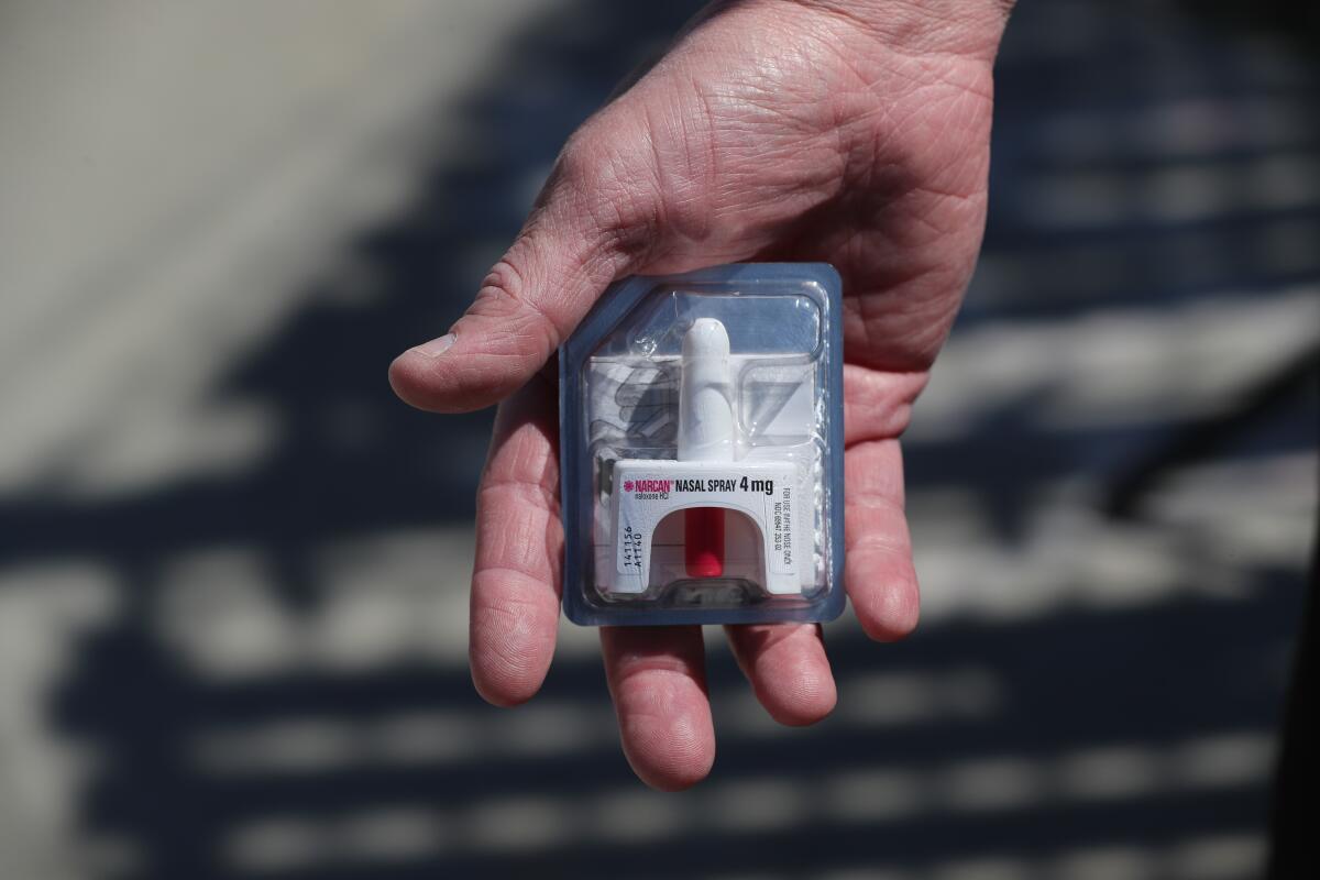 A close-up shot of a Narcan held in someone's hand.