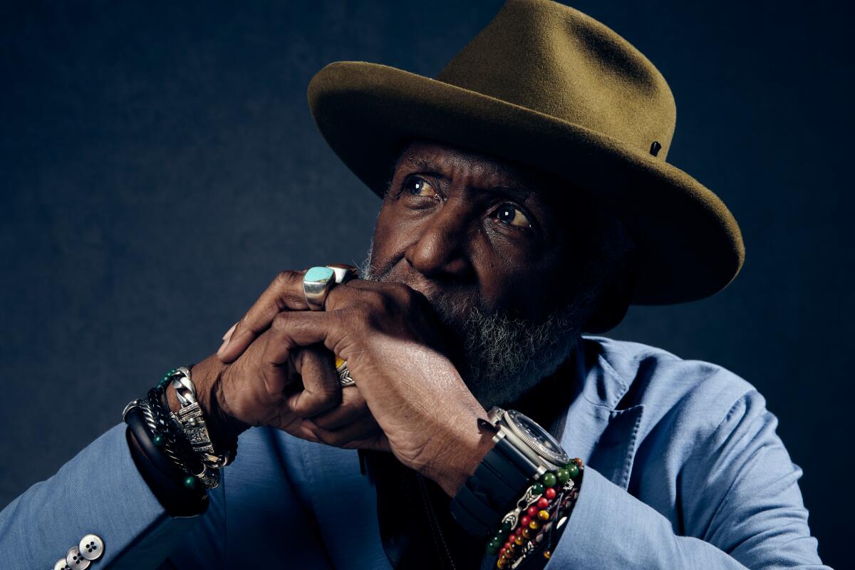 Richard Roundtree wears a green hat and a blue blazer. 