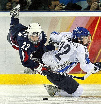Natalie Darwitz of the U.S. Women's hockey team keeps her eye on the puck after being upended by Finland's Saara Tuominen.