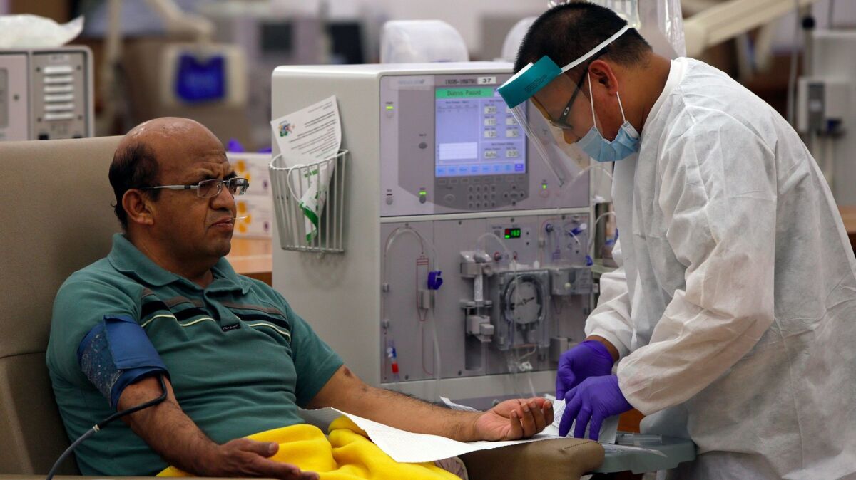 Giraldo Garcia, 54, waits for dialysis to start as patient care technician Leodegario Ventura, 33, prepares him for the process at DaVita Dialysis Center on Aug. 28, 2014, in Inglewood.