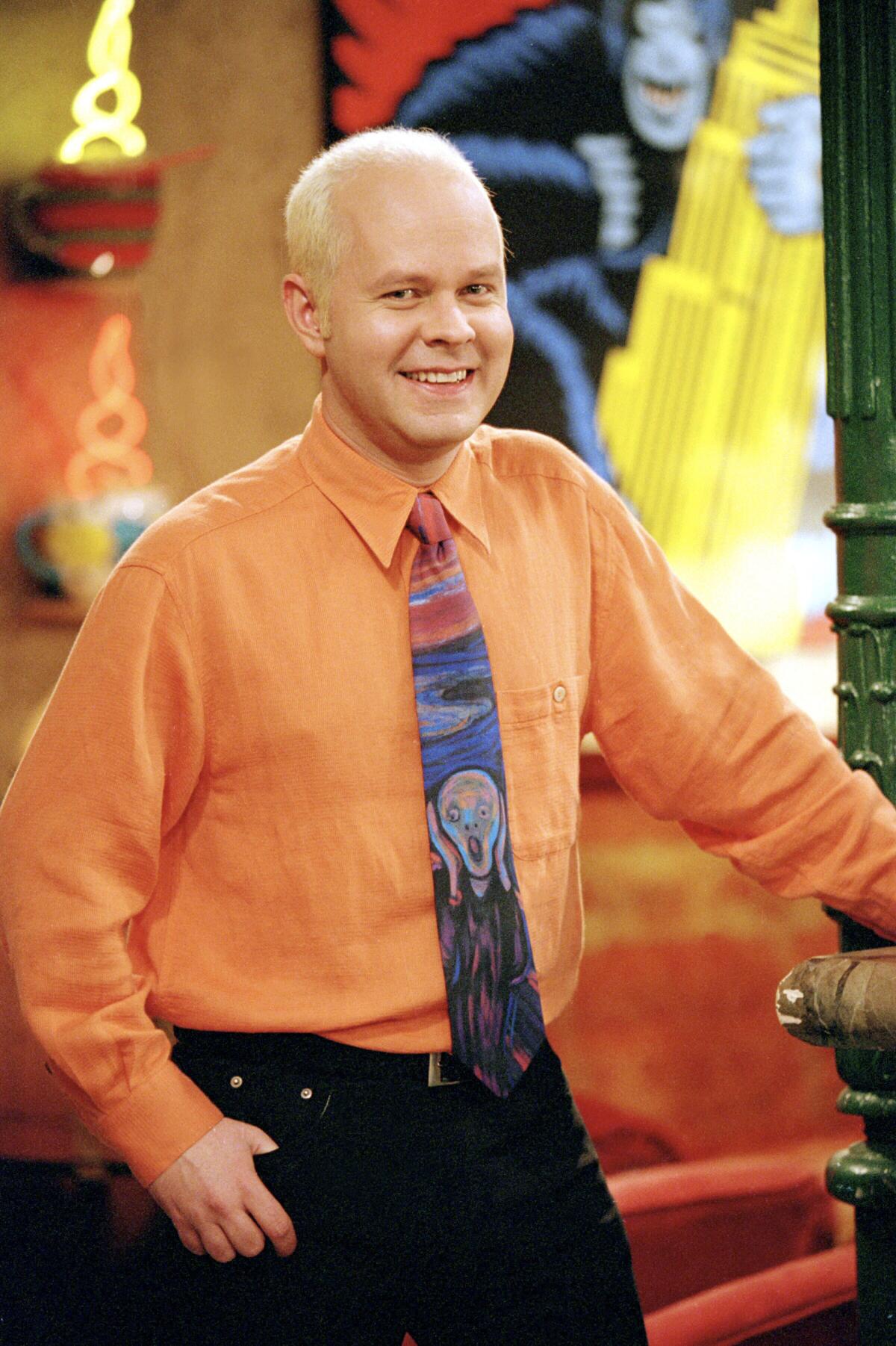 A man posing in an orange shirt and tie