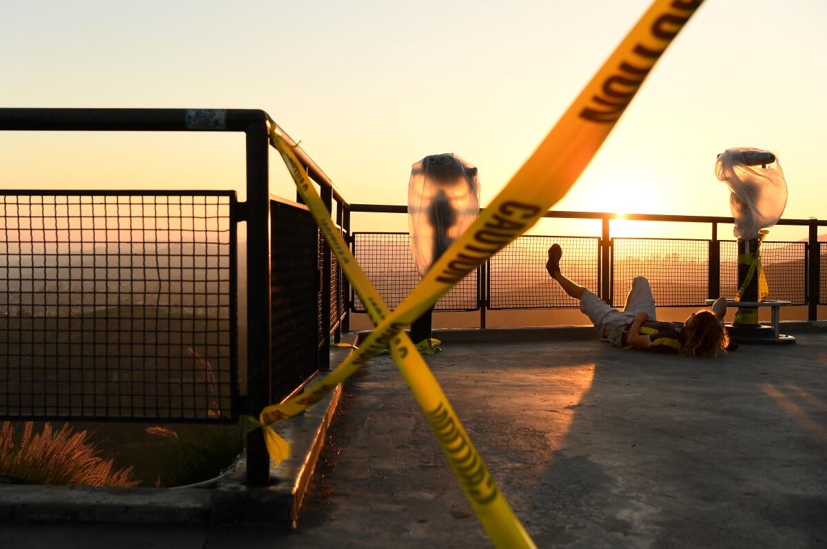 A man relaxes next to caution tape at Griffith Observatory on Tuesday, as the city remains locked down because of the coronavirus outbreak. 