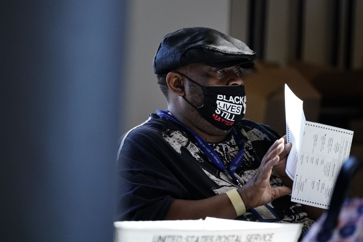 An Atlanta election worker in a "Black Lives Matter" mask holds a ballot as votes are counted Nov. 4.
