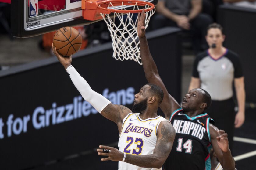 Los Angeles Lakers forward LeBron James (23) shoots past Memphis Grizzlies center Gorgui Dieng (14) during the first half of an NBA basketball game Sunday, Jan. 3, 2021, in Memphis, Tenn. (AP Photo/Wade Payne)