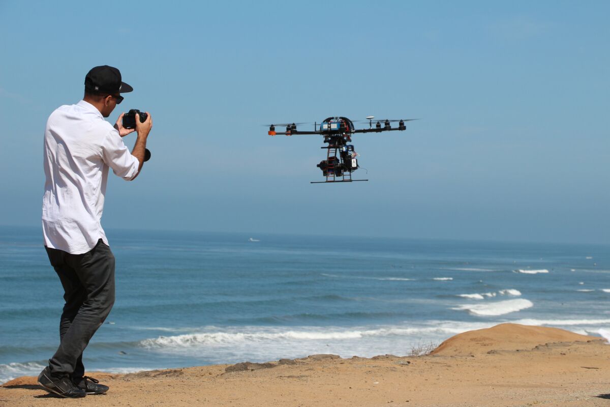 This image provided by Aerial MOB, LLC, shows their eight rotor Sky Jib Helicopter in San Diego, Calif., in August 2013. On the left is Shaun Khan, founder of FD Productions. The Federal Aviation Administration is expected to announce Thursday, Sept. 26, that it is granting permits to seven movie and television production companies to fly drones, including those from Aerial MOB, LLC, an important step toward greater use of the technology by commercial operators, said attorneys and a company official familiar with the decision. The seven companies have been working with the Motion Picture Association of America for two years to win approval from the FAA. (AP Photo/Aerial MOB, LLC, Tony Carmean) ** Usable by LA, DC, CGT and CCT Only **