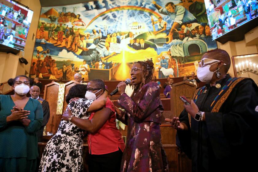 LOS ANGELES, CA - OCTOBER 30: Pastor Thema Bryant, second from right, also a professor of psychology at Pepperdine University, prays for Debra Lumpkin, of Lynwood, second from left, hugging her sister Dorothy Banks, at the First African Methodist Episcopal Church on Sunday, Oct. 30, 2022 in Los Angeles, CA. In January 2023 Dr. Bryant will become the president of the American Psychological Association, which represents more than 133,000 professionals. (Gary Coronado / Los Angeles Times)