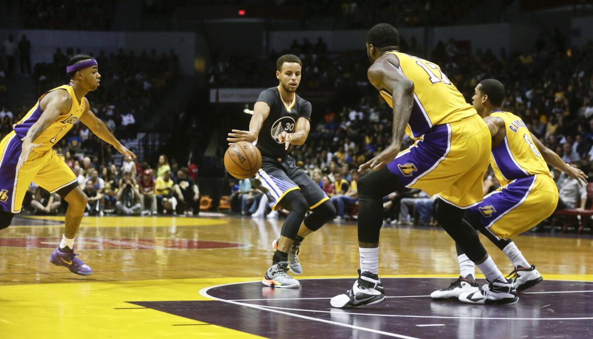 Golden State Warriors guard Stephen Curry splits the Lakers' defense with a fast-break pass during the first half of a preseason game on Oct. 17.